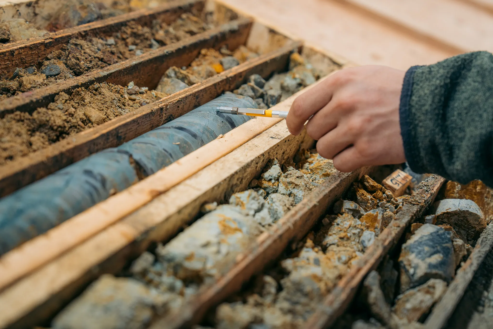 A geologist marking drill core in a core box at the Justin camp